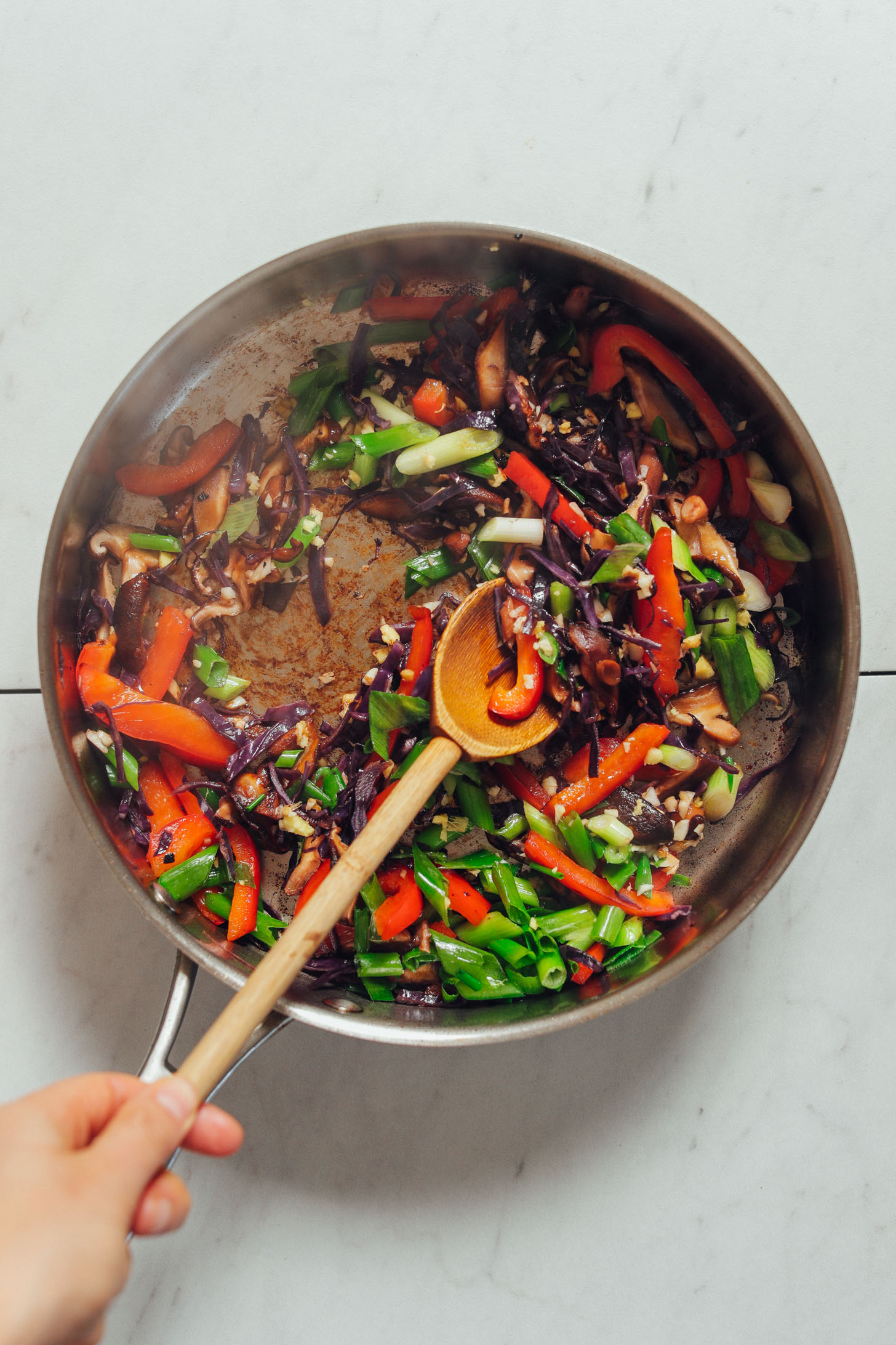 Using a wooden spoon to stir vegetables for a quick Tofu Stir Fry