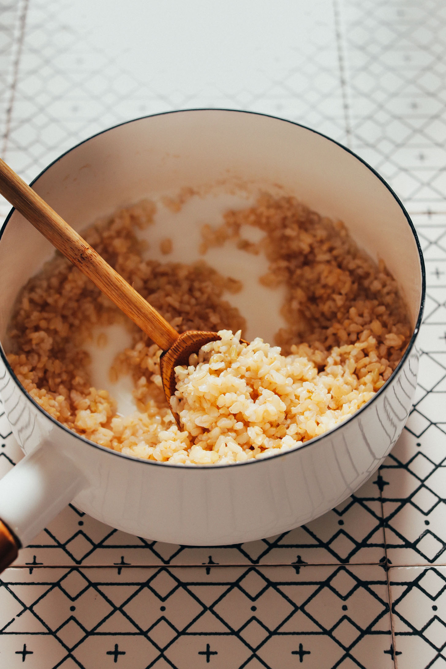 Wooden spoon in a pot of cooked brown rice