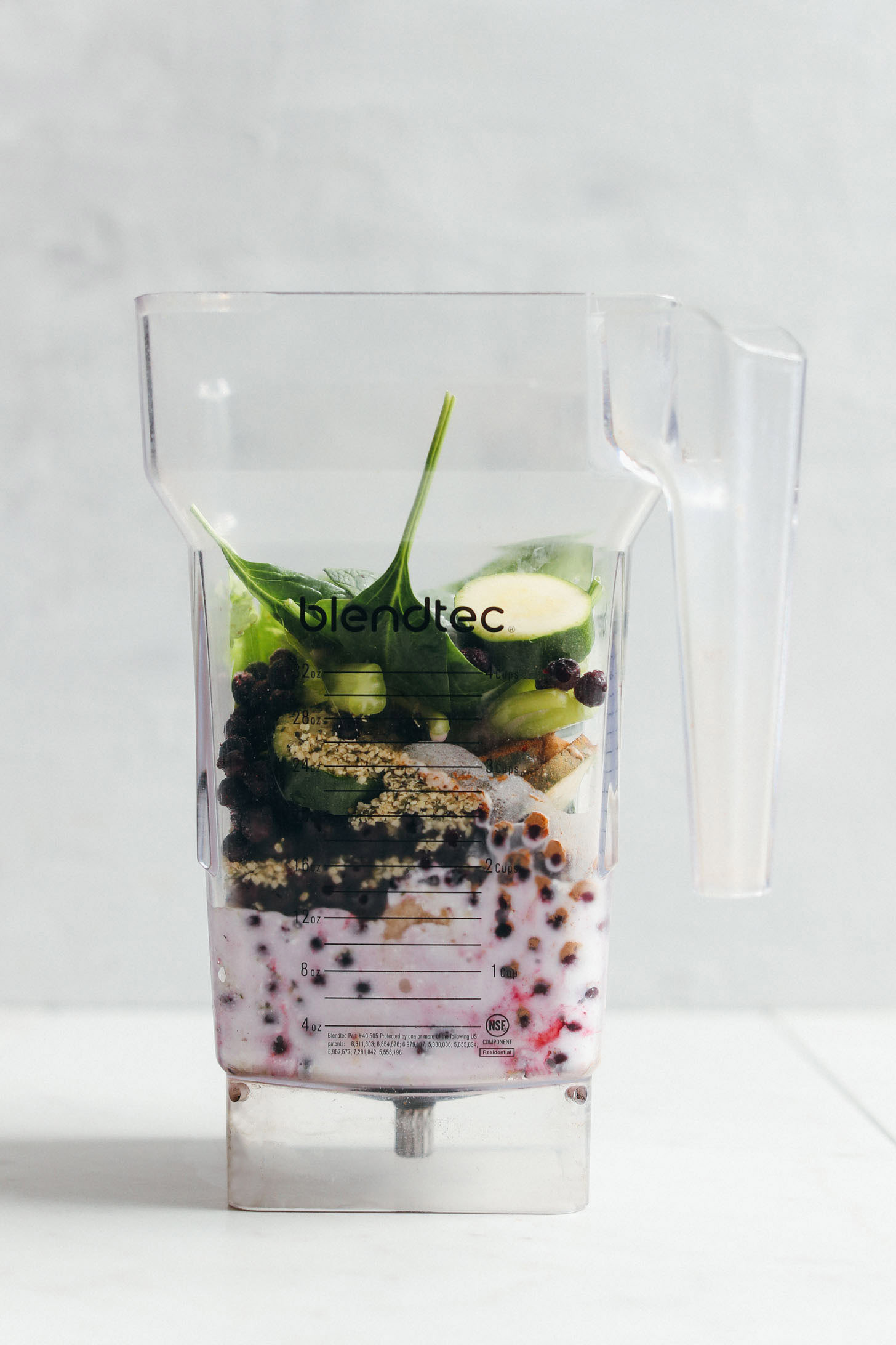 Blender filed with celery, zucchini, coconut milk, blueberries, spinach, banana, hemp seeds, and cinnamon ready to be blended into our Zucchini Berry Smoothie