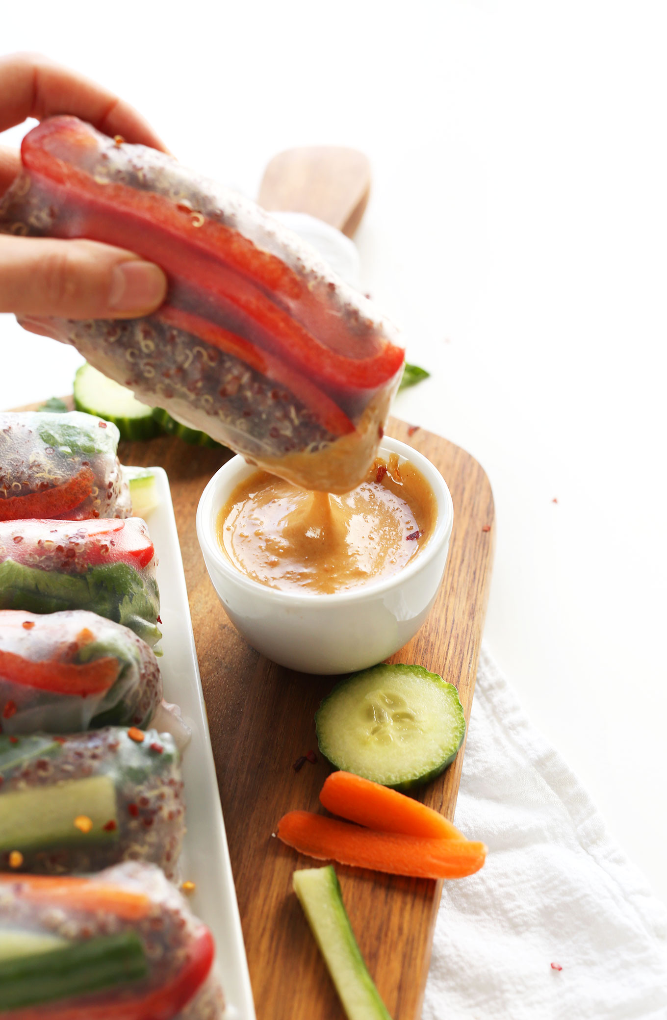 Dipping a salad roll into a bowl of homemade peanut sauce