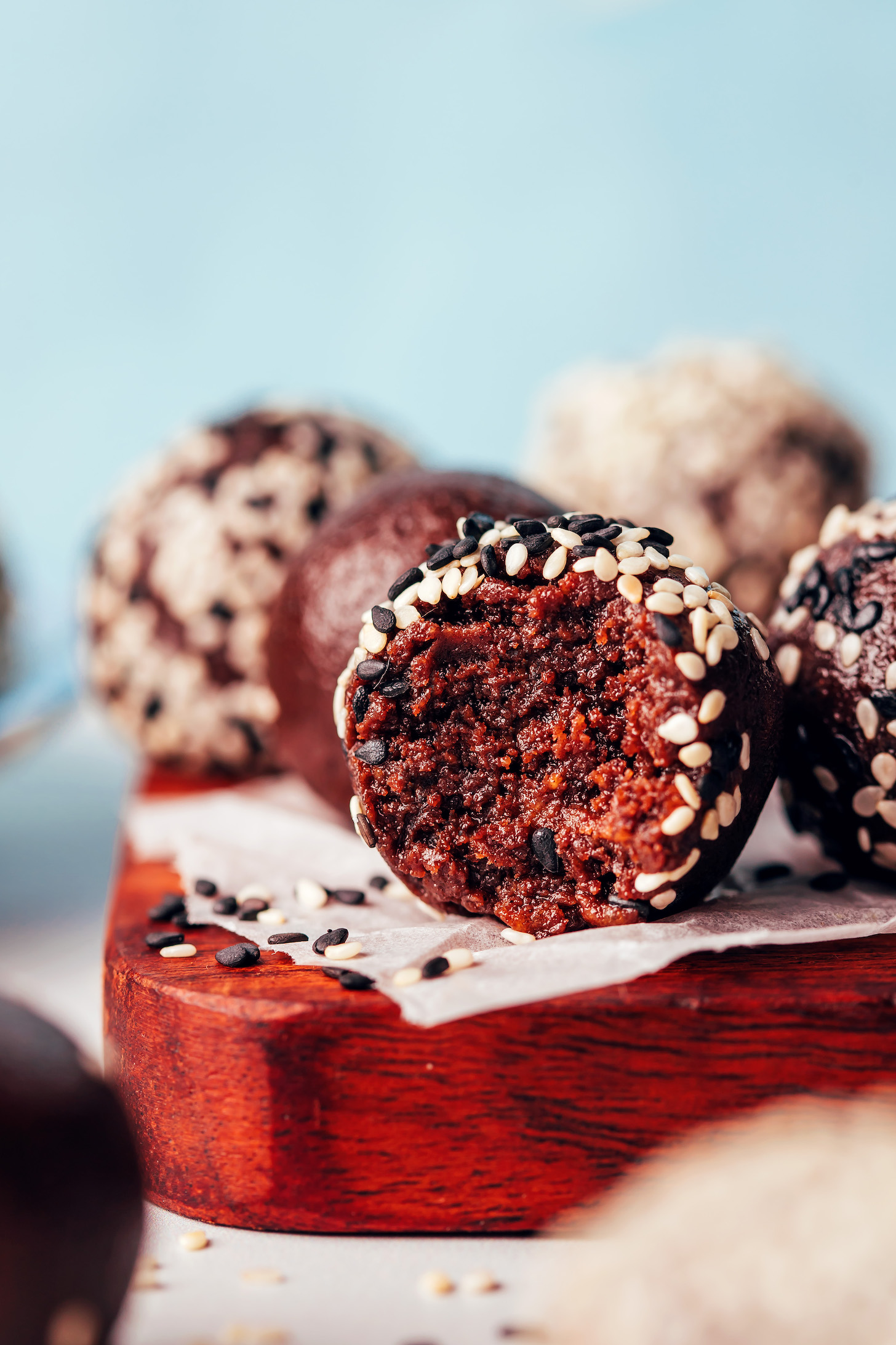 Close up shot of a bite of a vegan chocolate tahini truffle with more truffles in the background