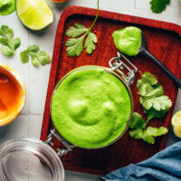 Overhead shot of a jar of vegan aji verde sauce surrounded by ingredients used to make it