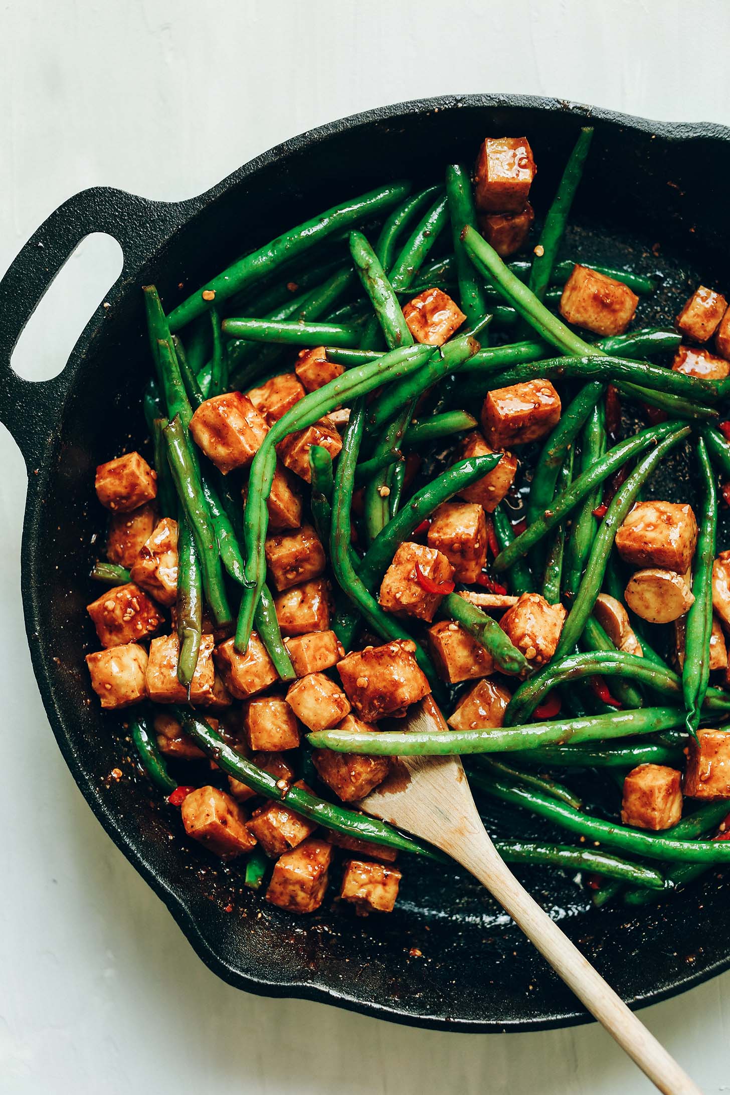 Cast iron skillet filled with green beans, tofu, and sauce for Almond Butter Tofu Stir-Fry