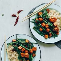 Two plates of our Almond Butter Tofu Stir Fry made with brown rice and green beans