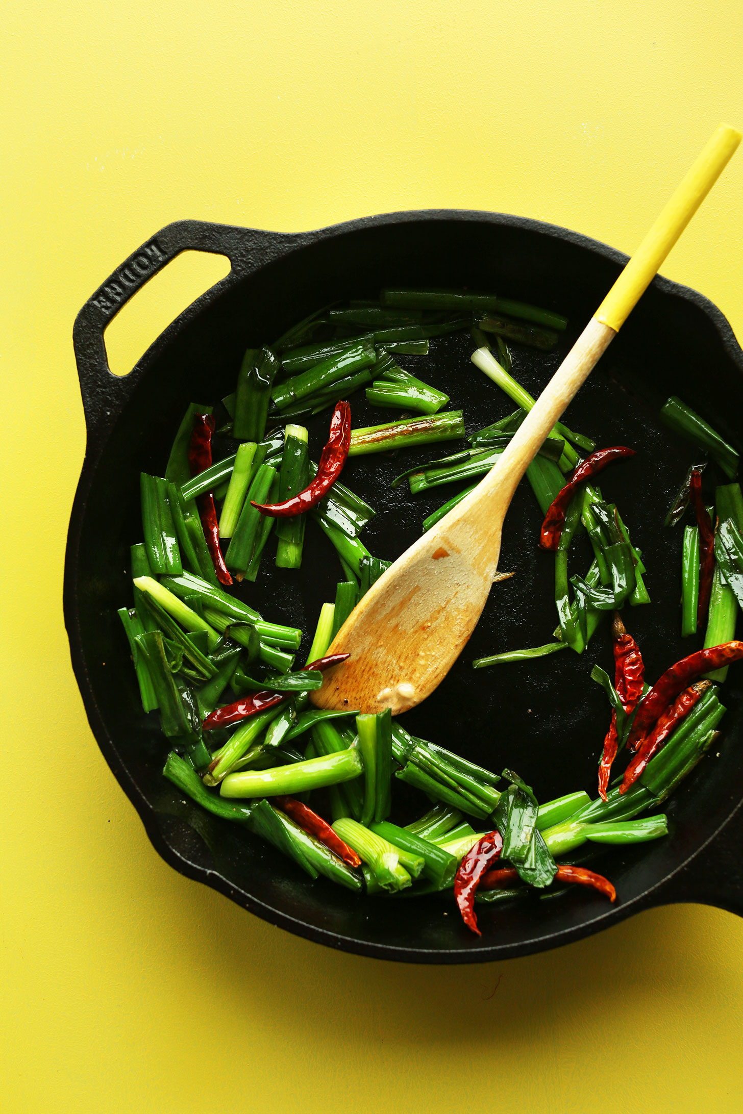 Sautéing green onions and red chilies in a cast-iron skillet