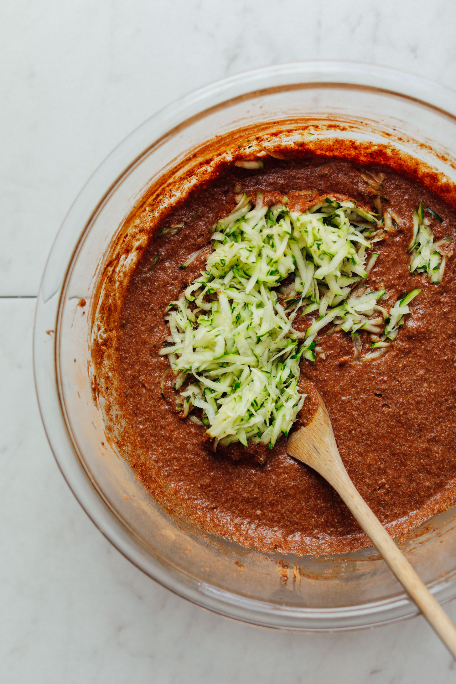 Stirring grated zucchini into batter for amazing Vegan Chocolate Chip Zucchini Bread