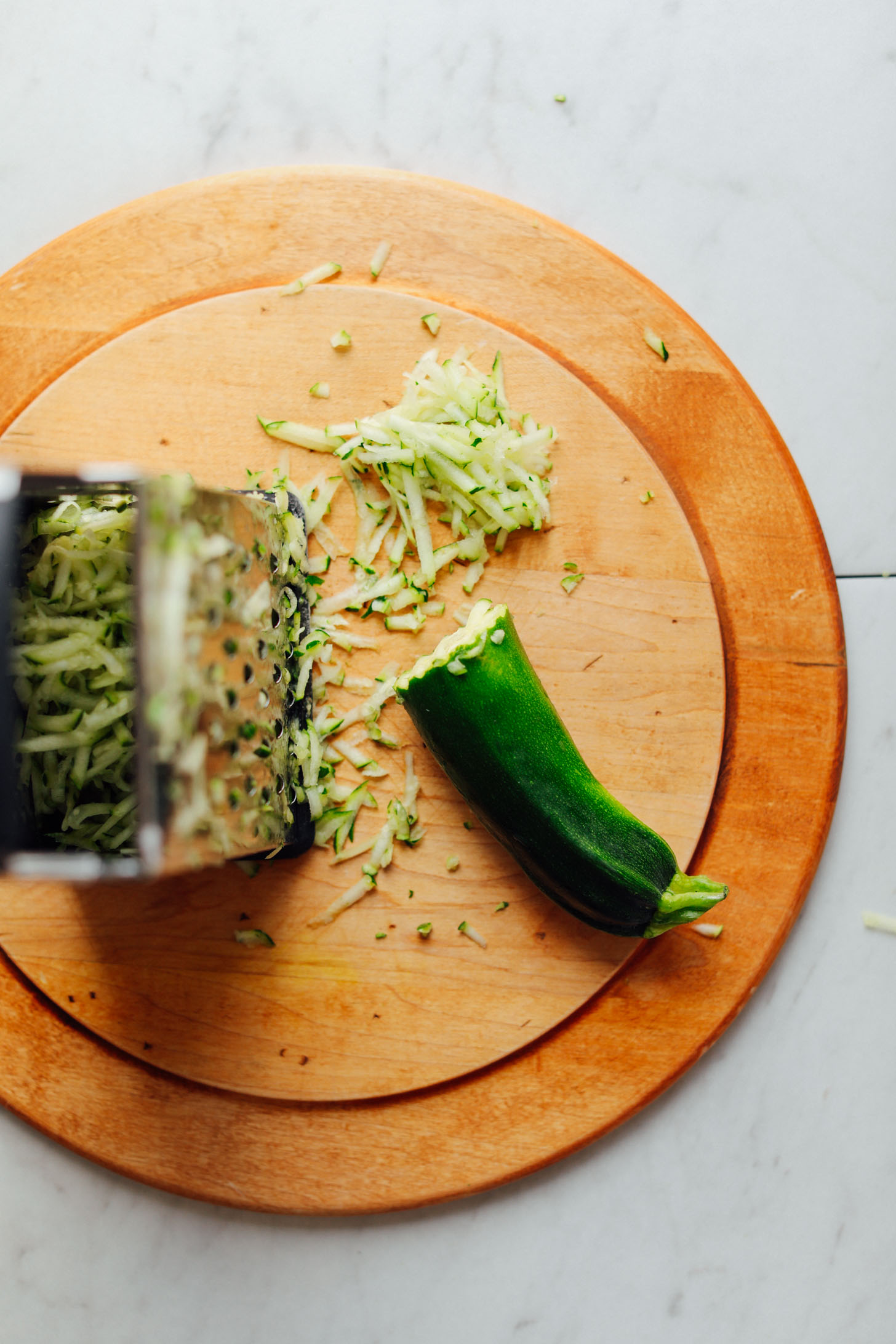 Shredding zucchini for making simple Vegan Chocolate Chip Zucchini Bread