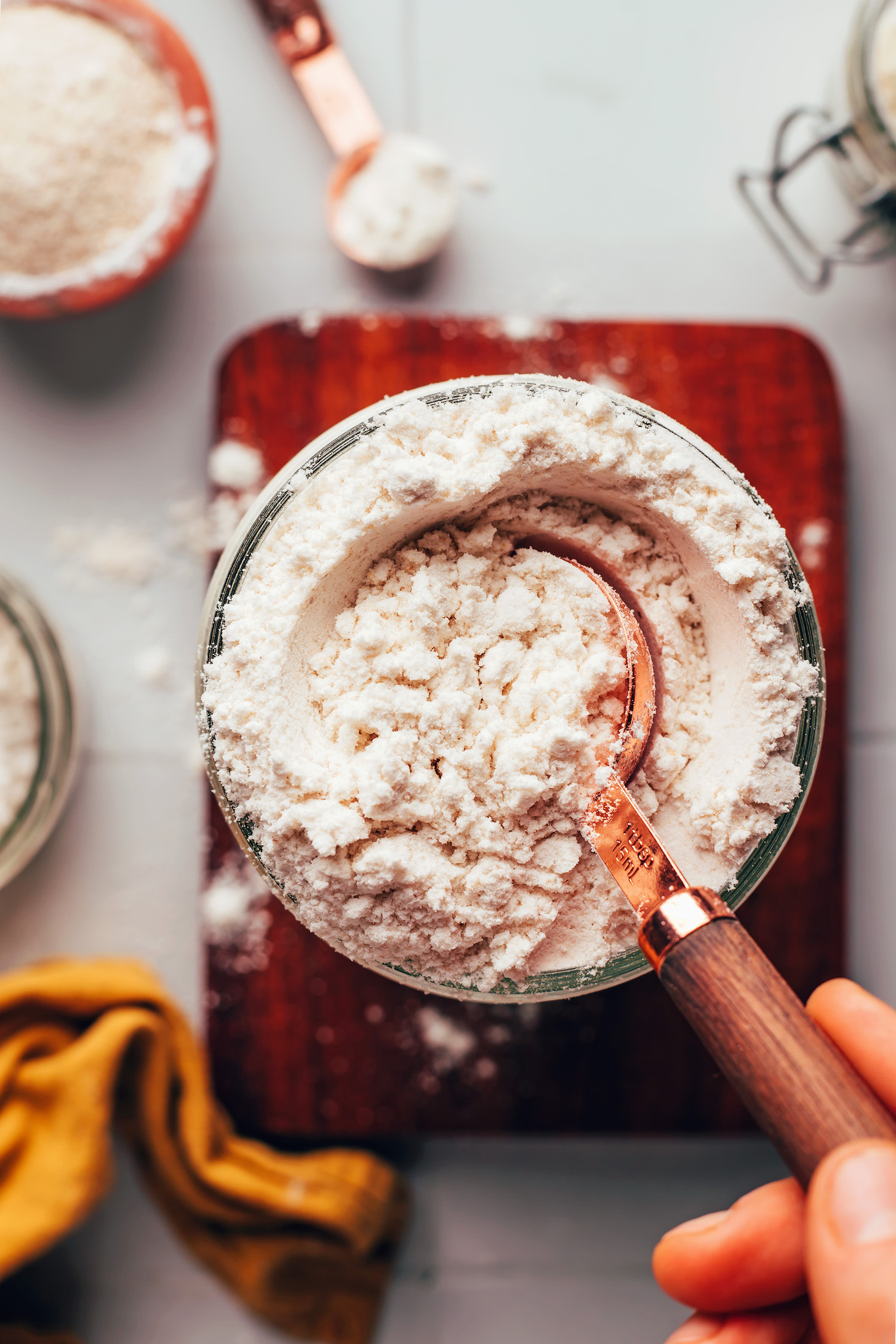 Picking up a spoonful of gluten-free flour blend from a jar