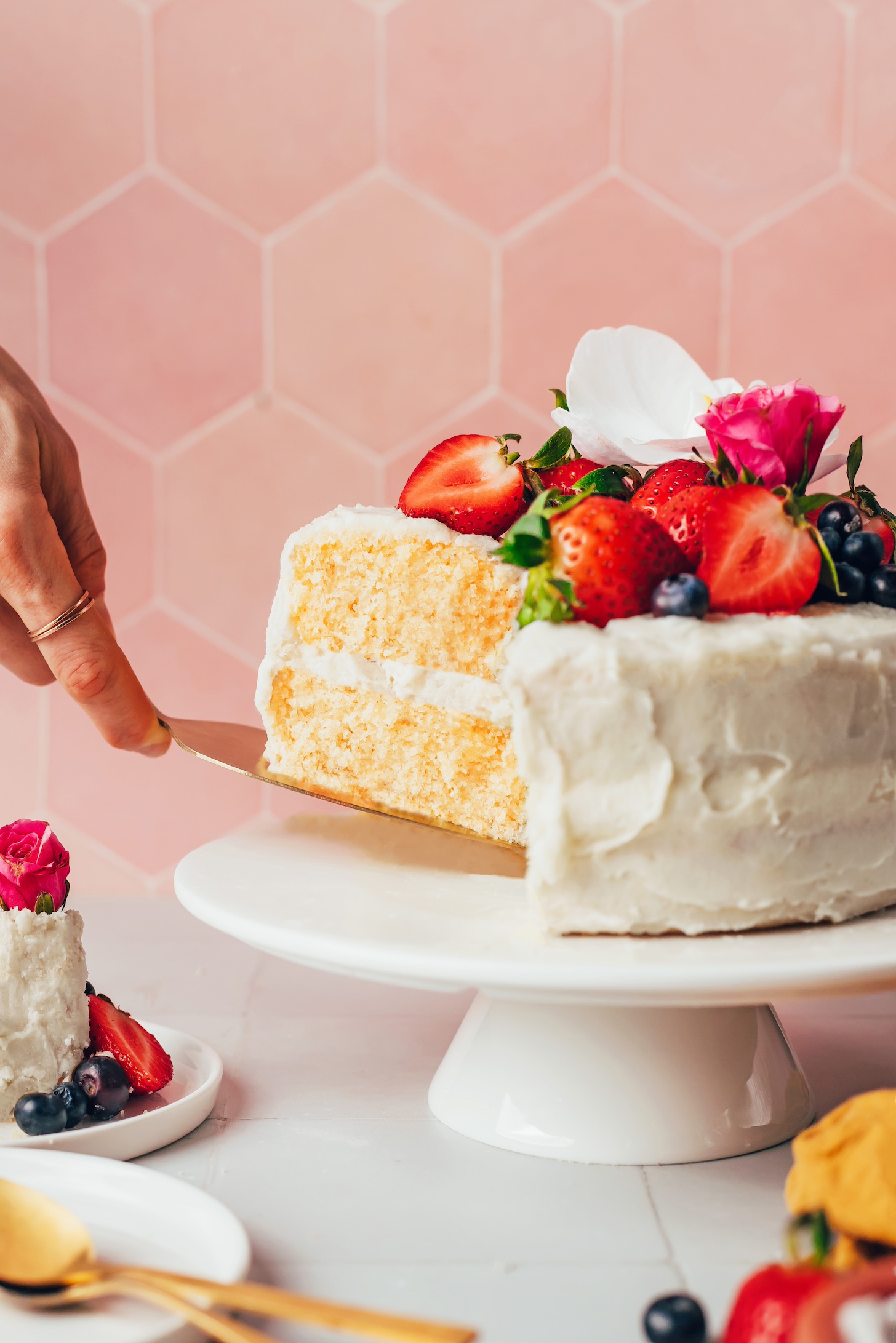 Removing a slice of our best gluten-free vanilla cake from a cake platter