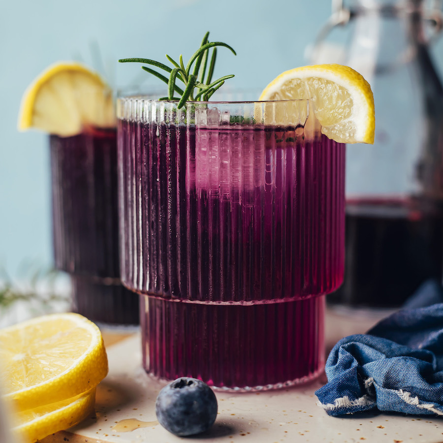 Lemon slice and fresh rosemary in glasses of blueberry ginger mocktails