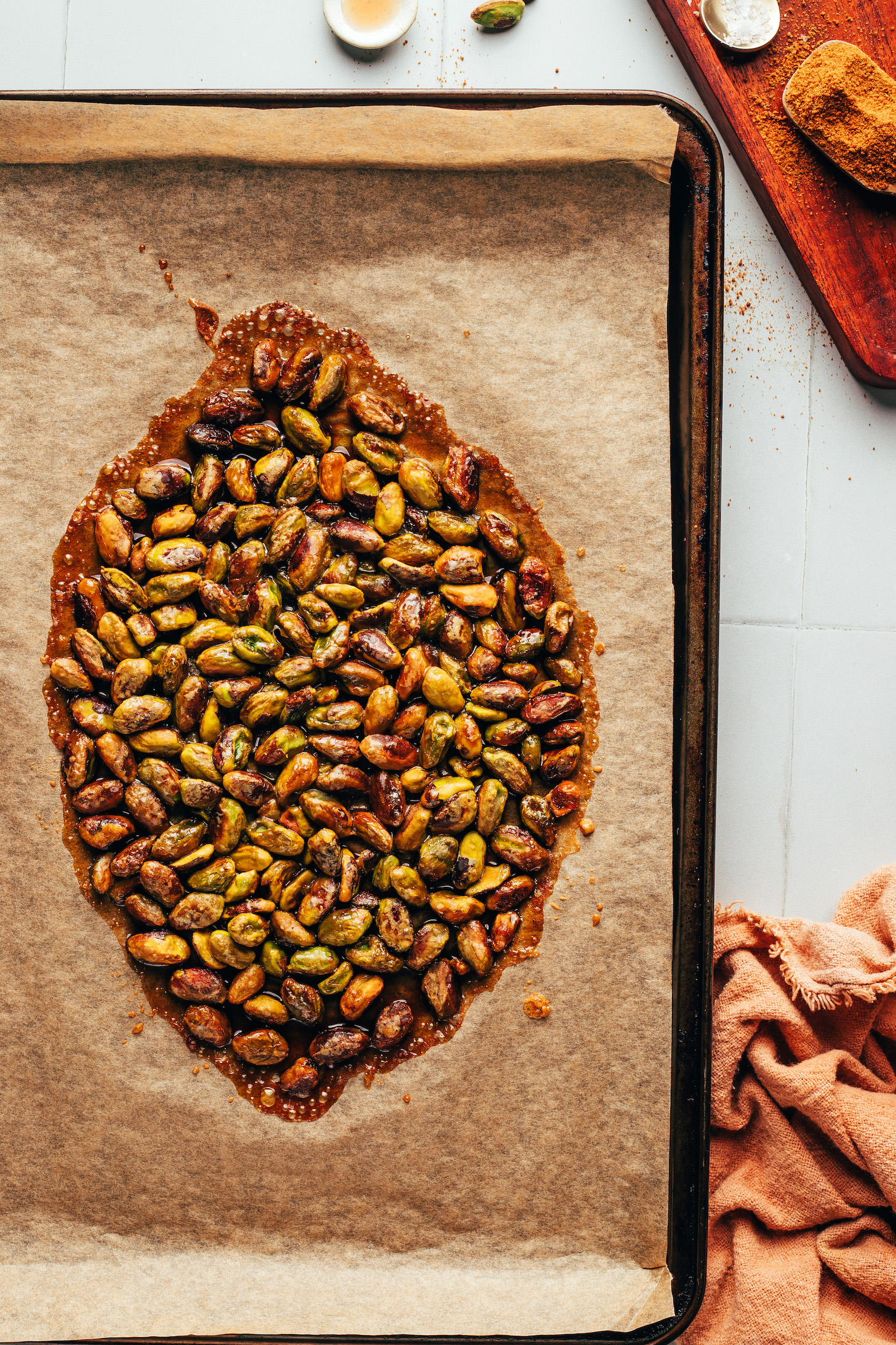 Freshly baked candied pistachios on a parchment-lined baking sheet