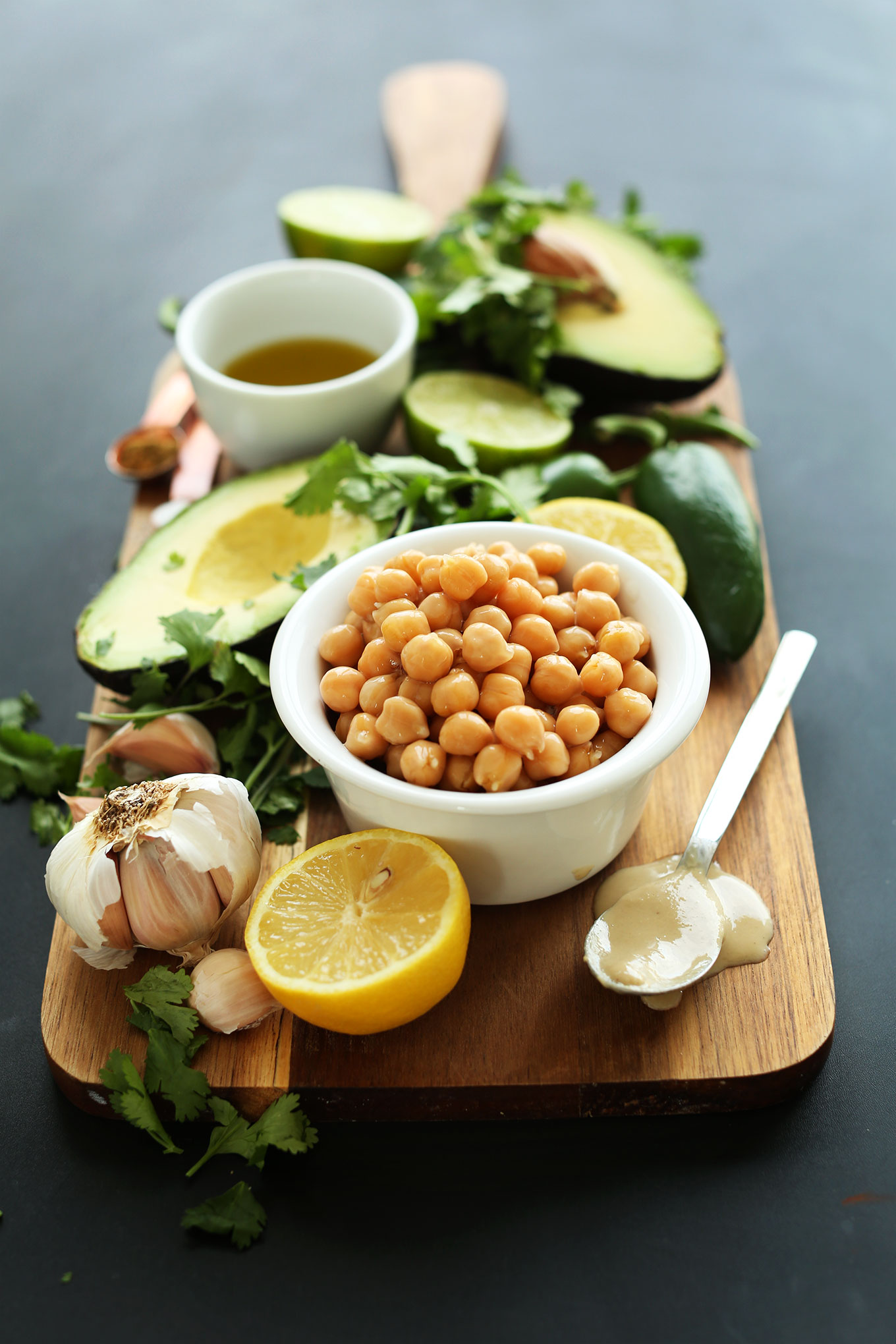 Wood board with chickpeas and other ingredients for making homemade Creamy Roasted Jalapeno Hummus