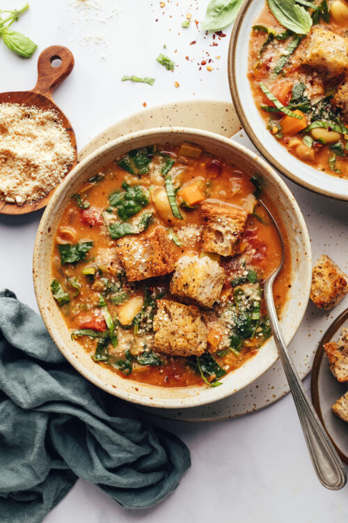 Two bowls of tuscan kale white bean soup topped with homemade croutons