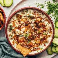 Cracker in a bowl of vegan caramelized onion dip