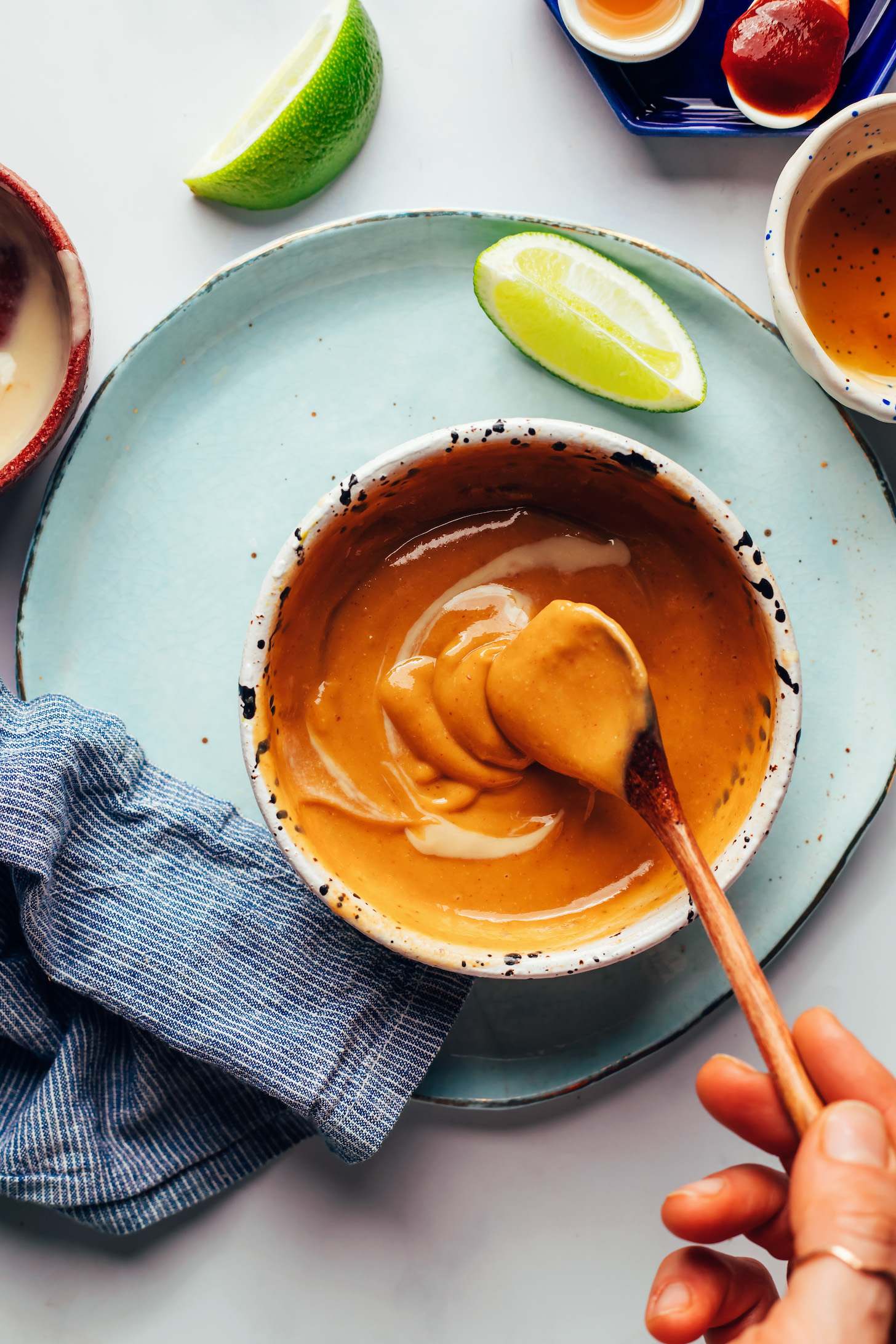 Sesame dipping sauce sliding off a spoon into a bowl