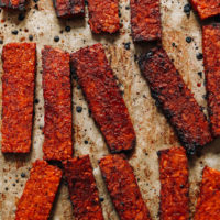 Strips of vegan tempeh bacon on a baking sheet