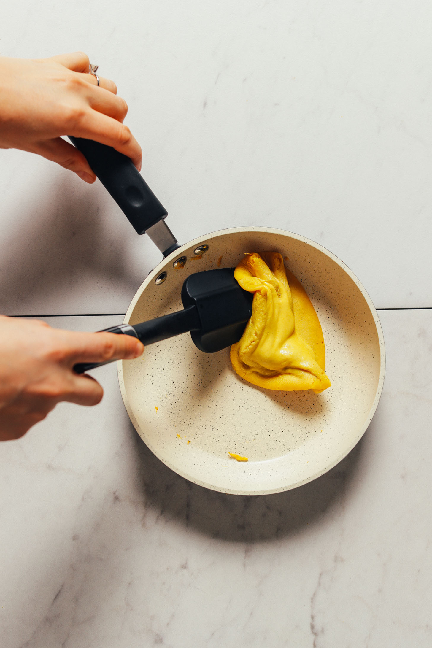 Moving a homemade vegan scrambled egg in a pan to help it cook evenly