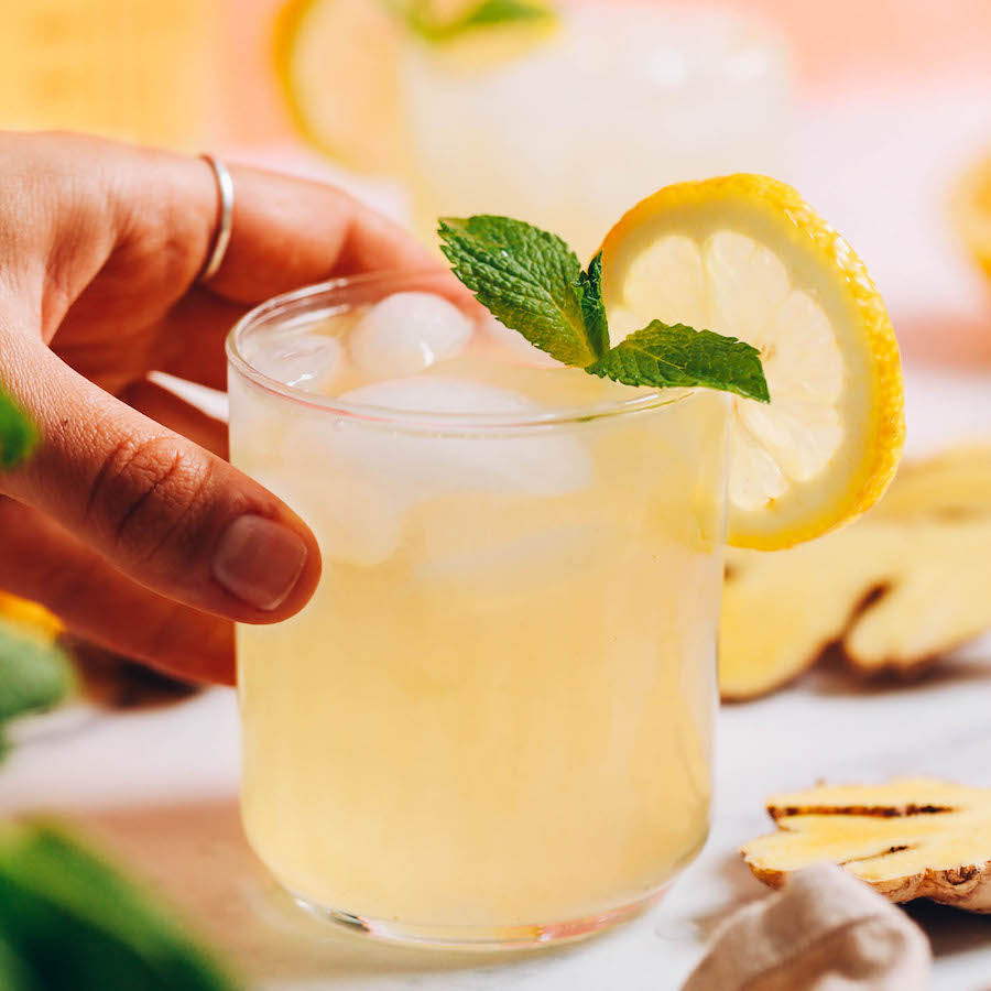 Hand reaching in to pick up a glass of ginger lemonade