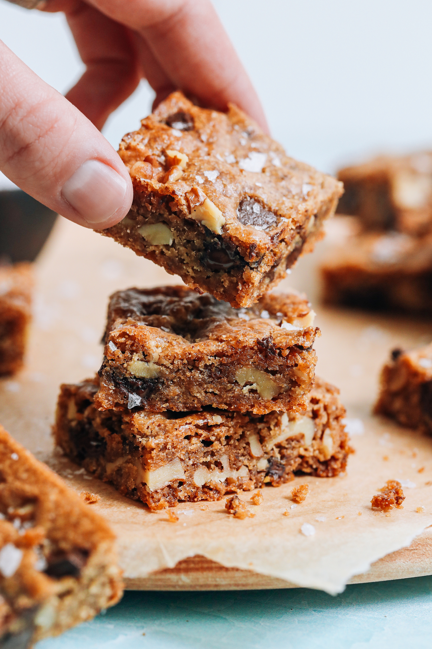 Picking up a vegan gluten-free chocolate chip cookie bar from a stack