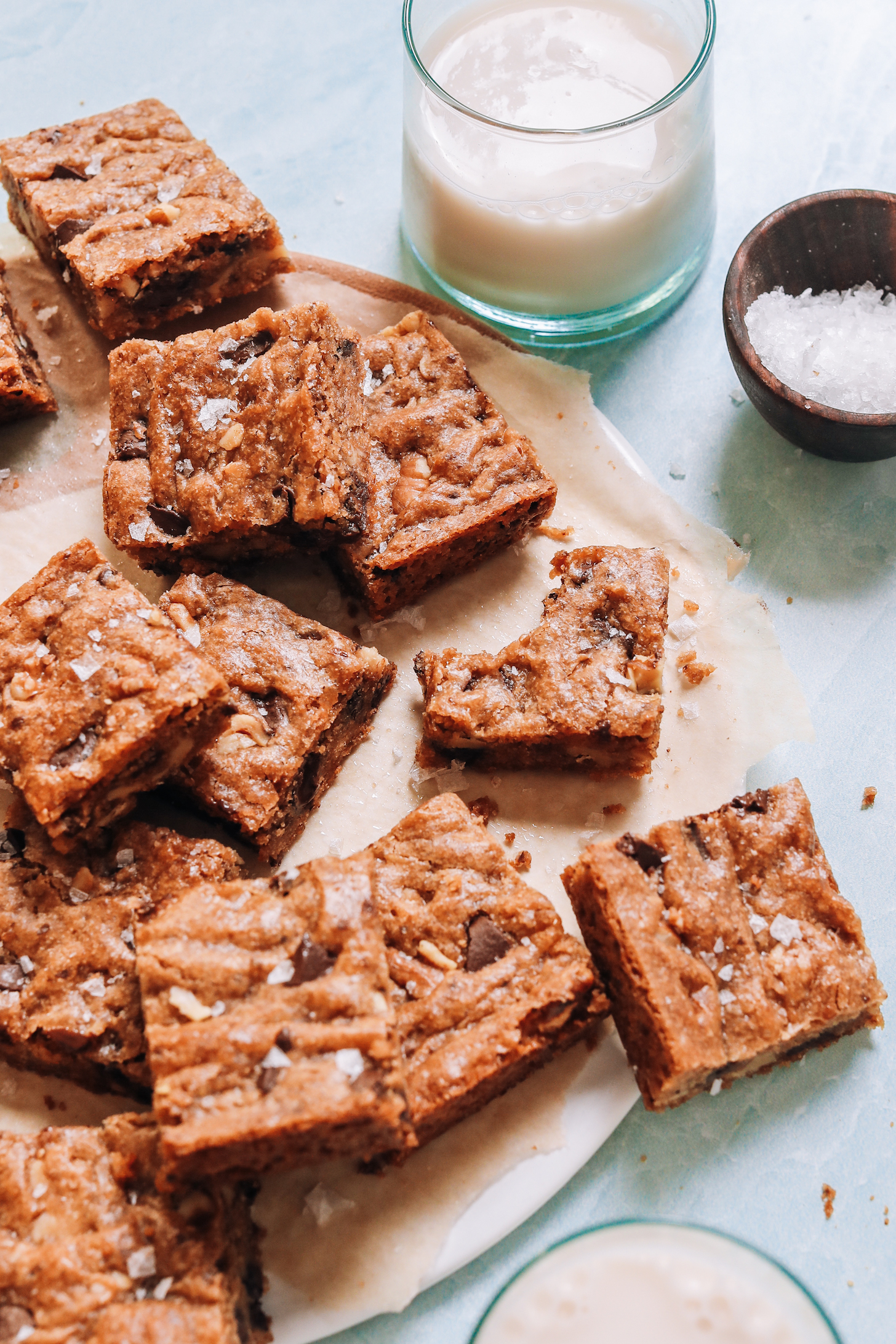 Dairy-free milk and flaky salt next to a batch of chocolate chip cookie bars