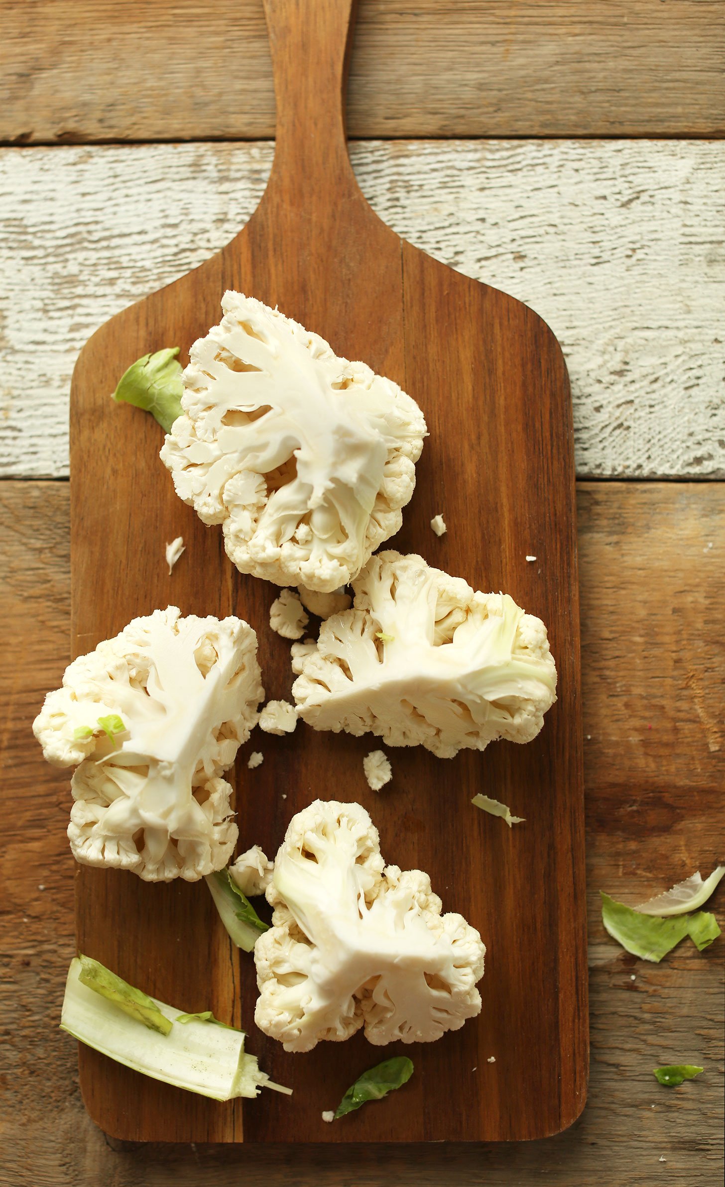 Wood cutting board with a quartered cauliflower