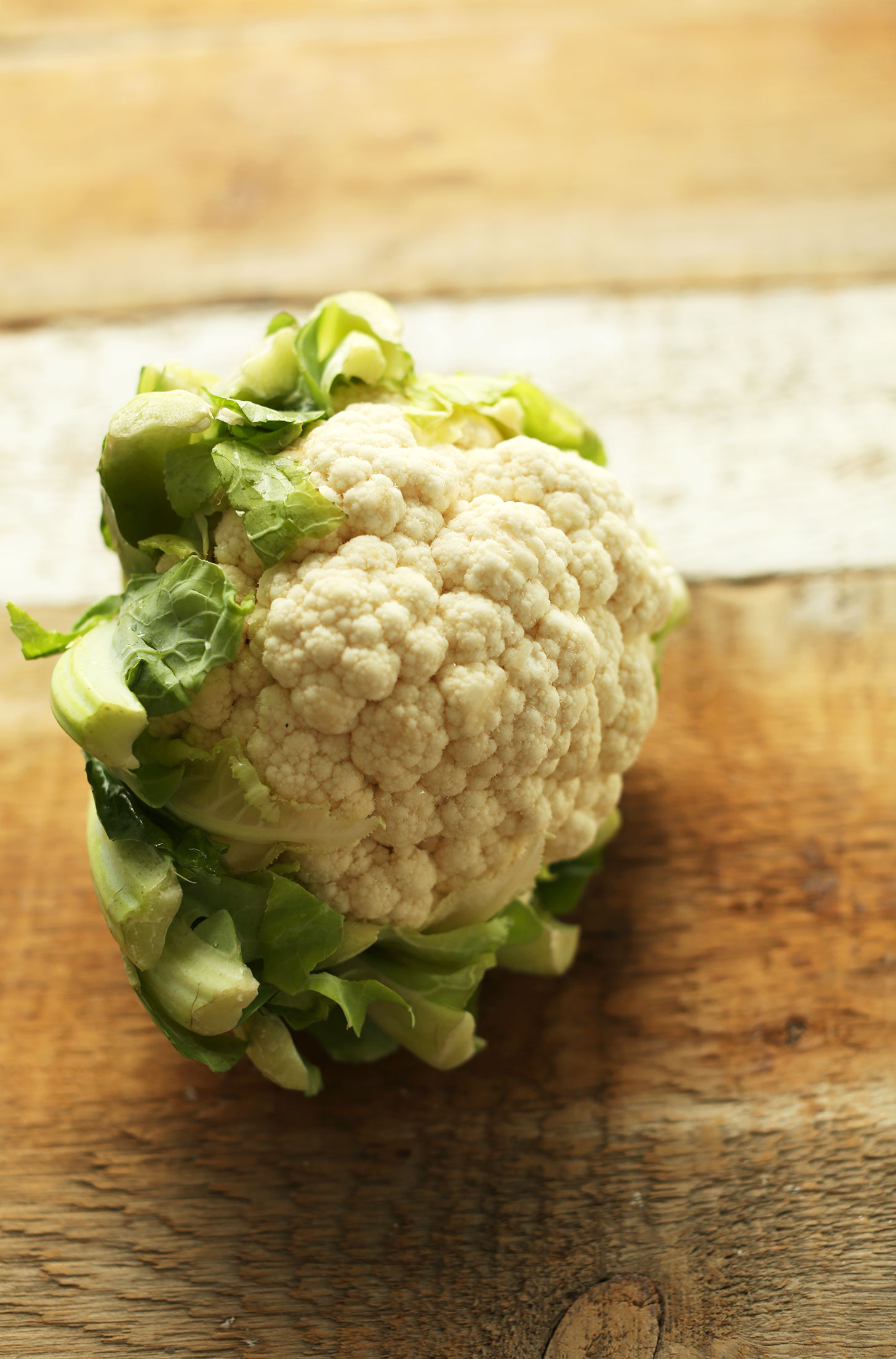 Whole cauliflower on a wood cutting board