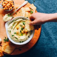 Using a pita chip to scoop up a bite of homemade Hummus from Scratch