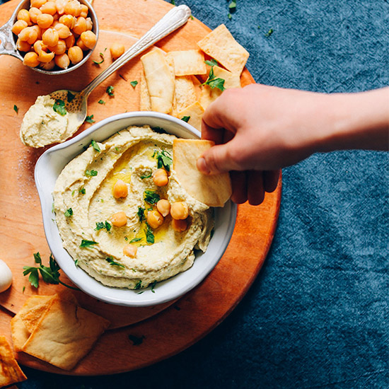 Using a pita chip to scoop up a bite of homemade Hummus from Scratch