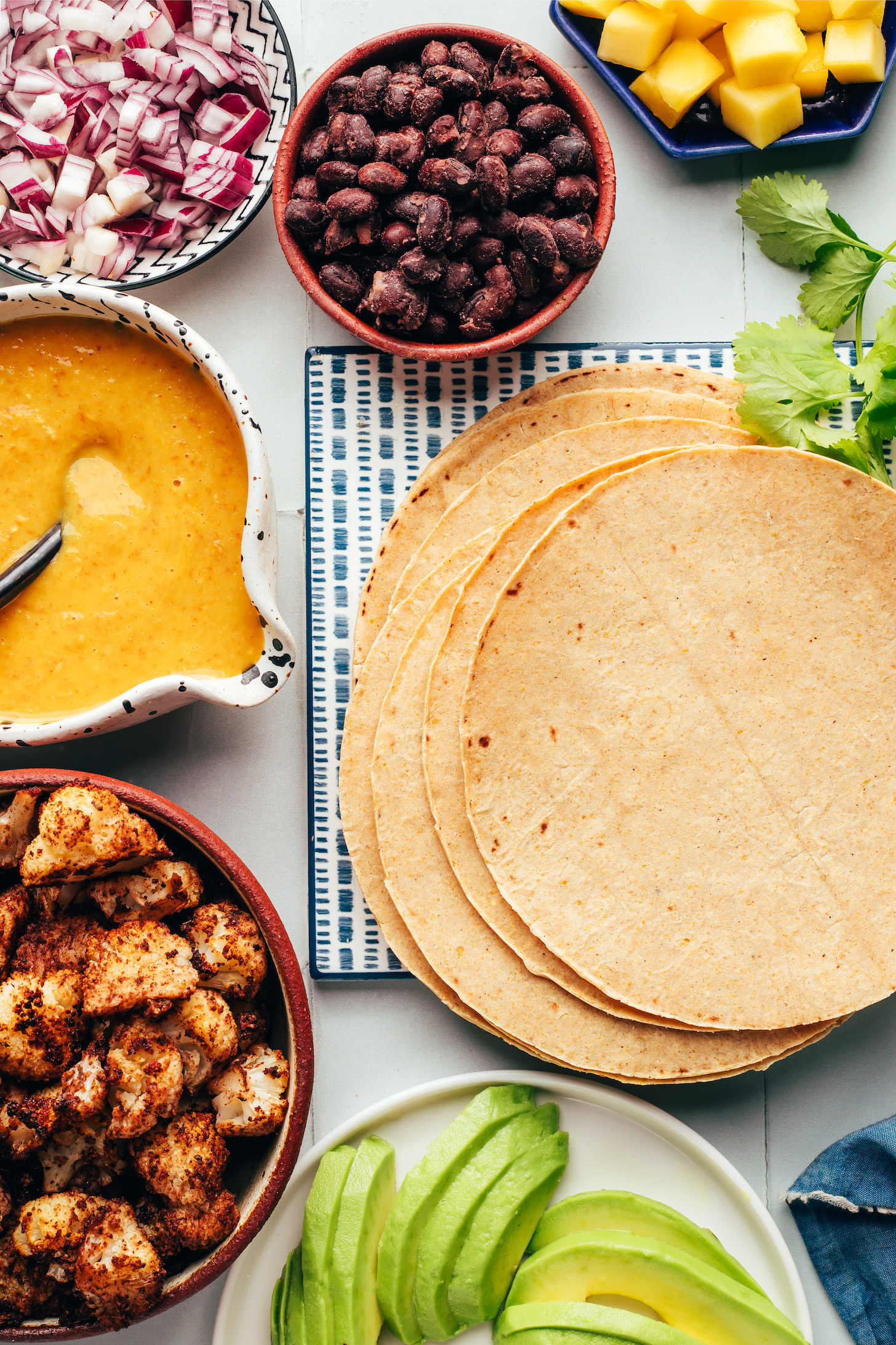 Mango, black beans, red onions, hot sauce, jerk cauliflower, avocado, corn tortillas, and cilantro