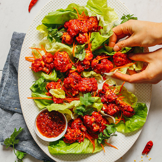 Grabbing some Korean-Inspired Cauliflower Wings wrapped in lettuce leaves with shredded carrot