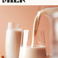 Pouring homemade cashew milk from a pitcher into a glass for our guide on how to make cashew milk