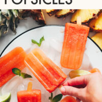 Picking up a homemade fruit popsicle from a plate