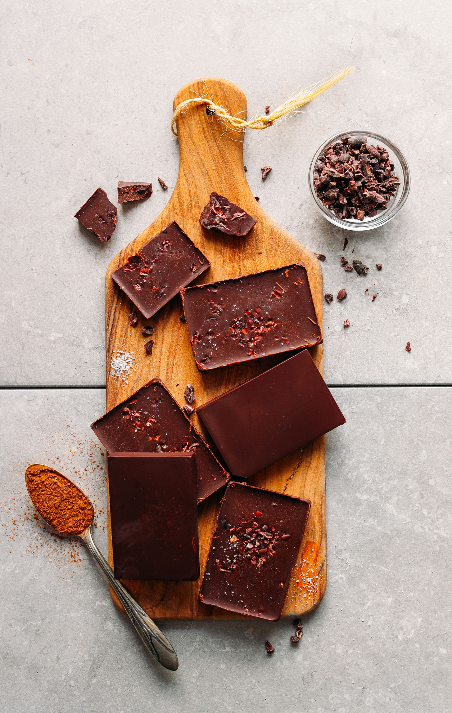 Wood cutting board displaying DIY Vegan Dark Chocolate bars with cacao nibs