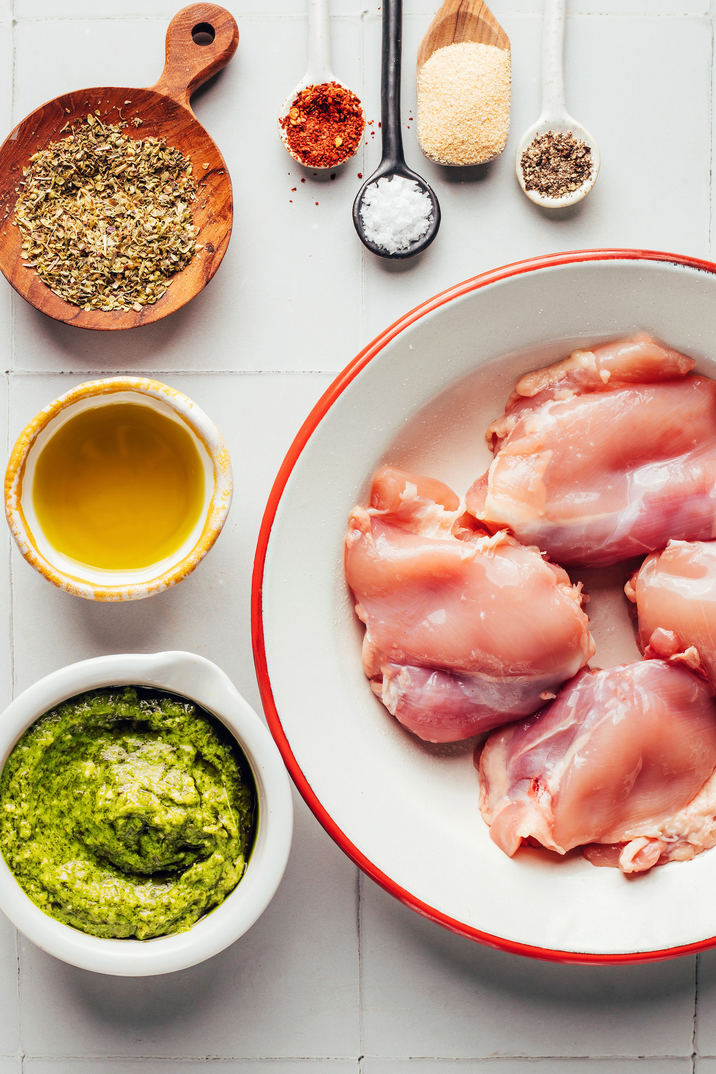 Boneless skinless chicken thighs, pesto, olive oil, dried Italian herbs, red pepper flakes, salt, garlic powder, and black pepper