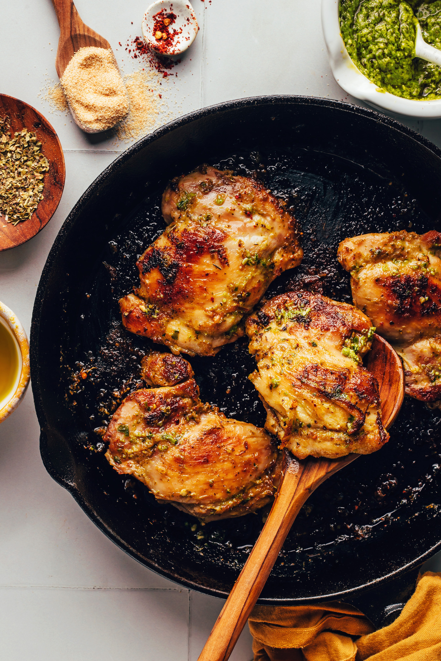 Golden brown pesto baked chicken thighs in a cast iron skillet