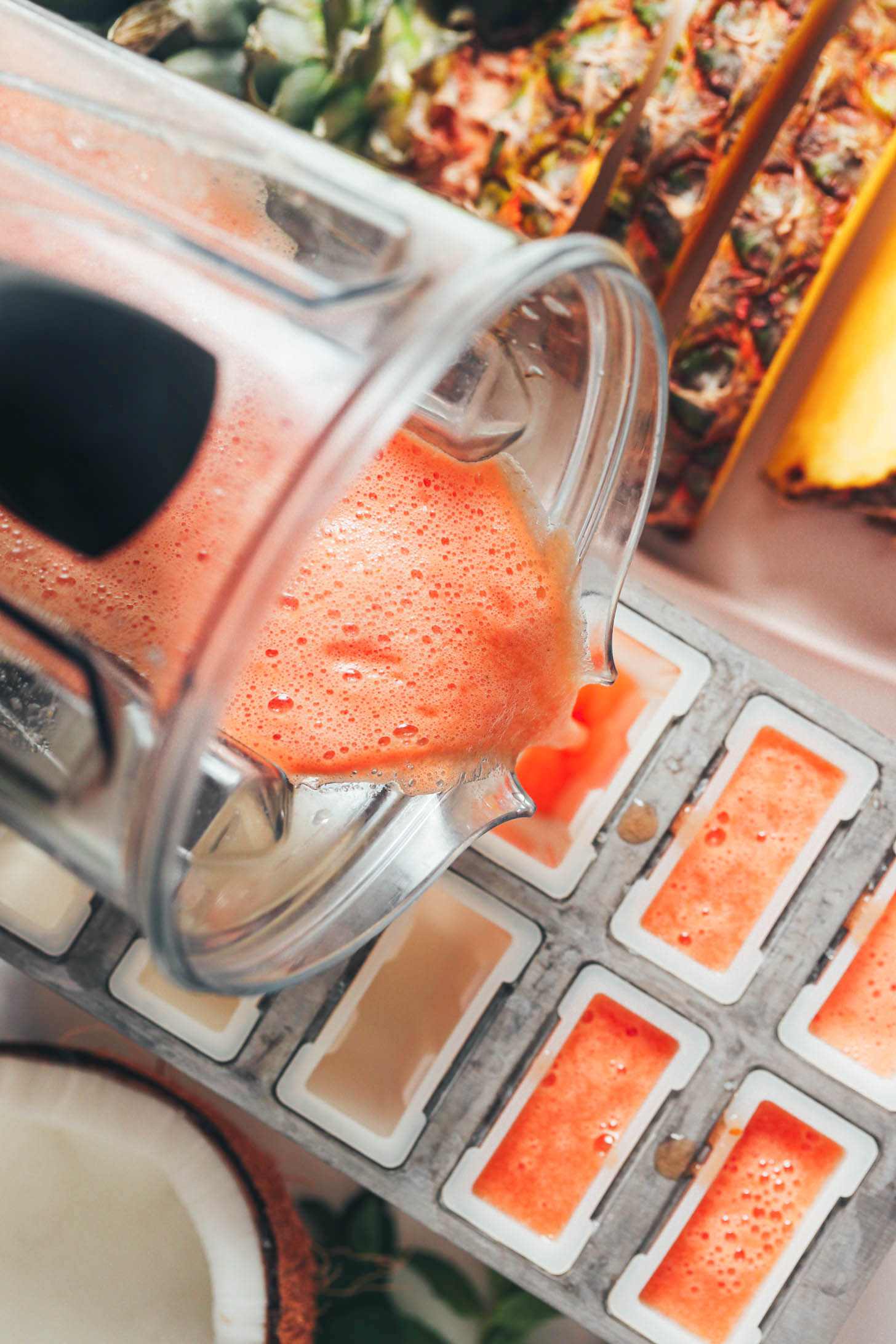 Pouring a watermelon pineapple mixture into a popsicle mold