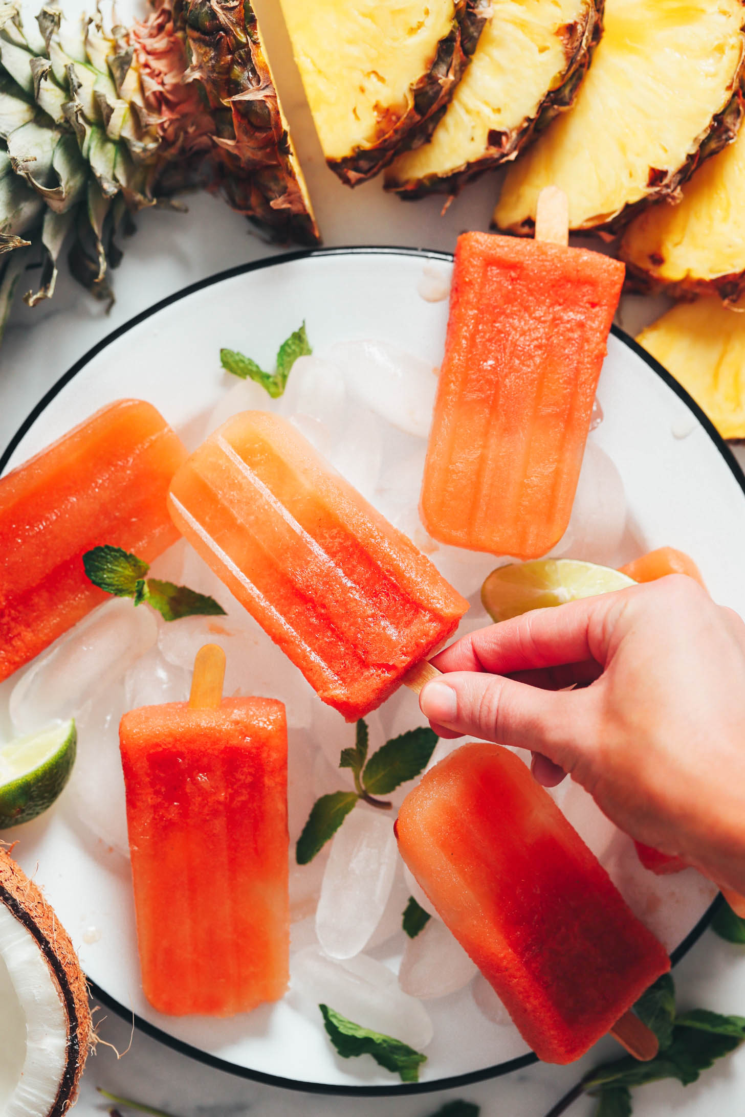 Hand picking up a tropical fruit popsicle made with whole fruit