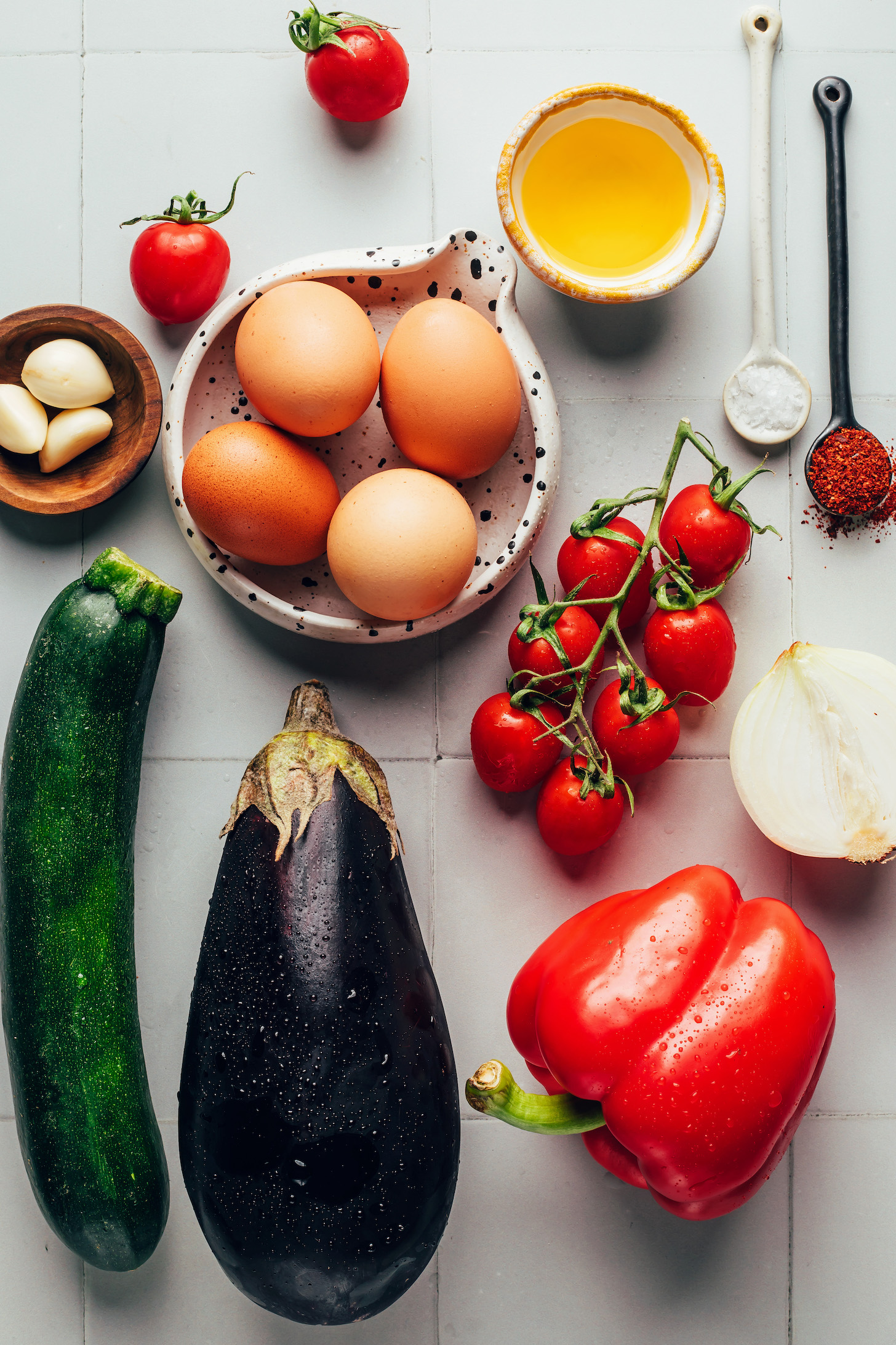 Garlic, eggs, cherry tomatoes, olive oil, salt, red pepper flakes, onion, red bell pepper, eggplant, and zucchini