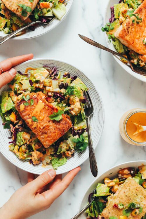 Hands holding a bowl of our smoky summer salad with lime-crusted salmon