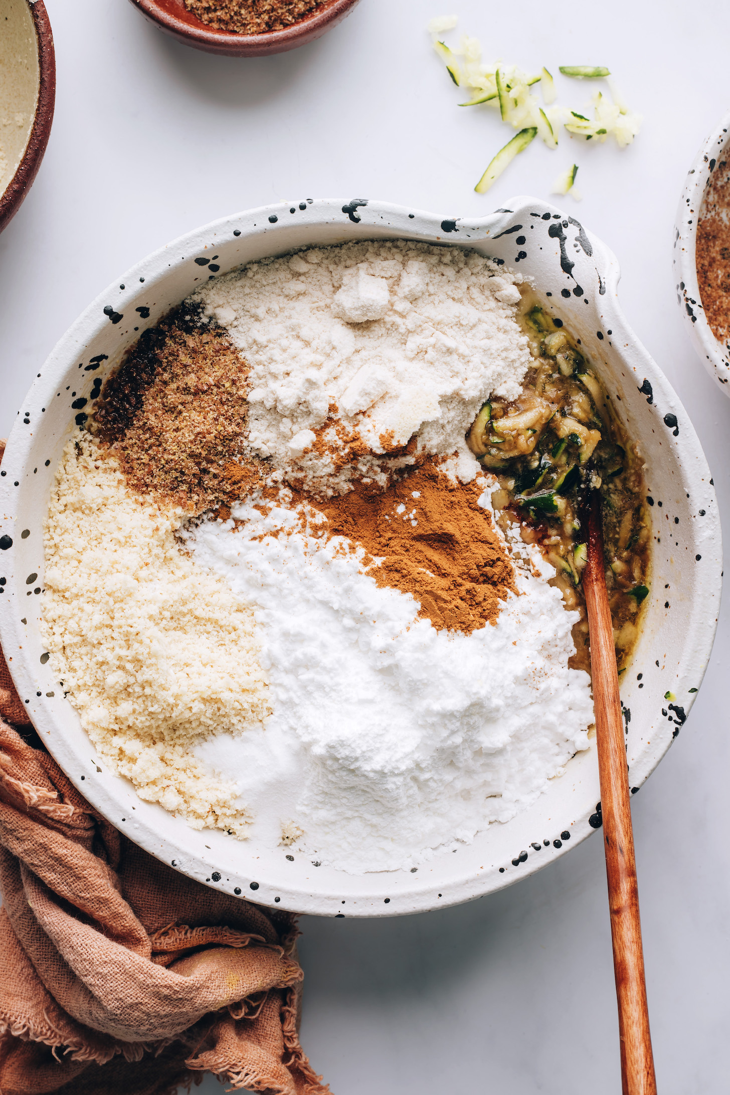 Gluten-free flours, cinnamon, and flaxseed meal in a mixing bowl over the wet ingredients