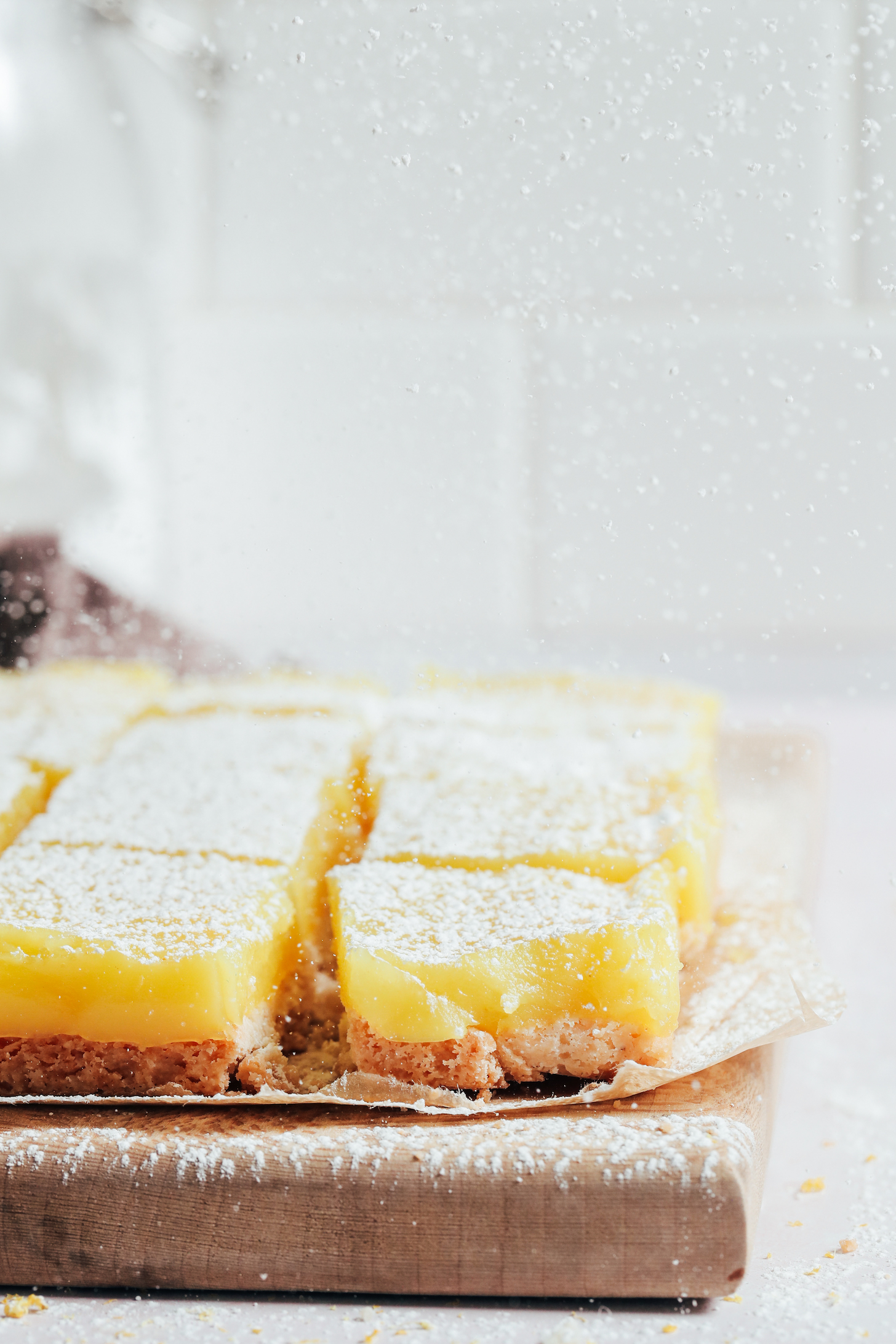 Sprinkling powdered sugar over homemade vegan gluten-free lemon bars