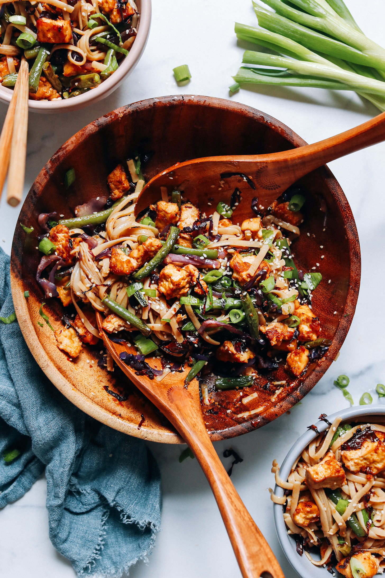 Large bowl and serving bowls of vegan ginger sesame noodles with crispy tofu