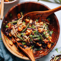 Using wooden spoons to toss a bowl of noodle stir-fry