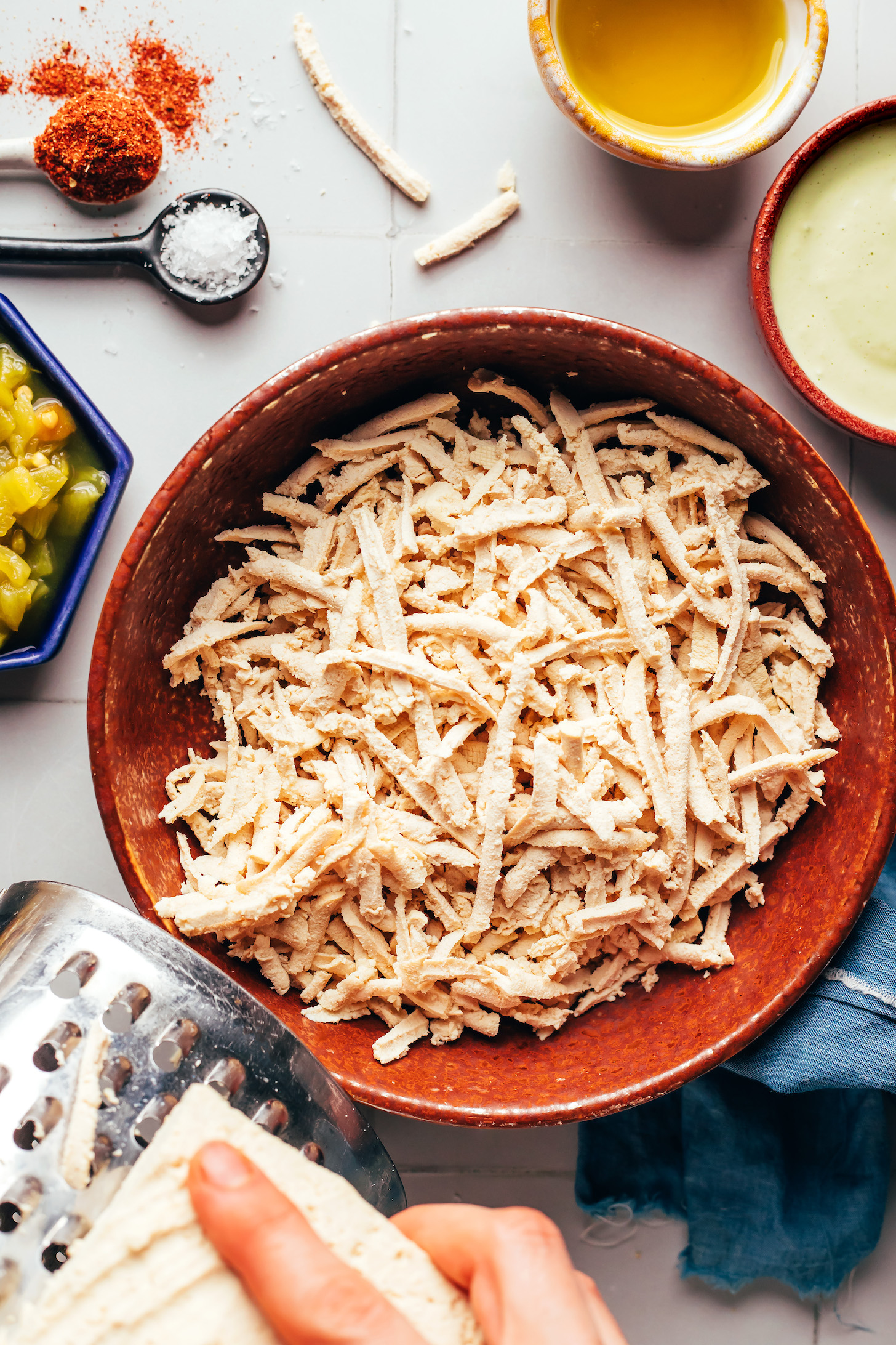 Shredding tofu on a box grater into a bowl