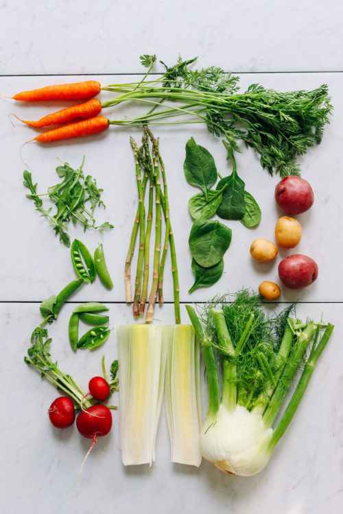 Assortment of spring vegetables such as carrots, fennel, asparagus, and radishes